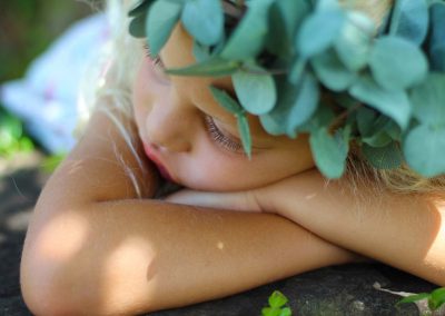 beautiful girl portrait lying on stone with plant crown