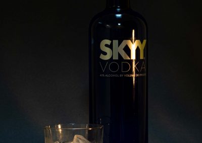 skyy vodka with glass and ice cubes on black background